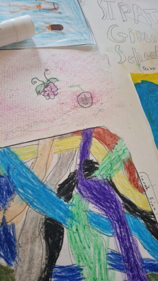 A collection of colourful children's drawings on paper. One features bold strokes of blue, green, and purple. Another has simple sketches of flowers. Playful and creative.