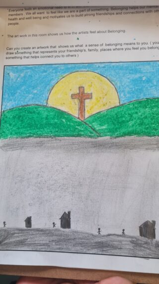 A child's drawing features a large cross on a green hill beneath a bright yellow sun in a blue sky. Gray ground with silhouetted figures in the foreground.