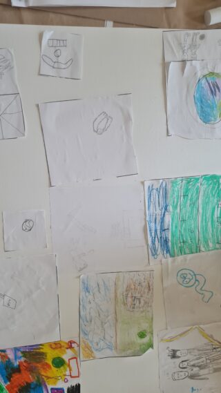 A wall displays children's drawings, featuring colourful scribbles and sketches of various shapes and scenes, creating an atmosphere of creativity and playfulness.