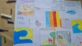 A collage of colourful children's drawings on paper. It includes nature scenes, abstract shapes, and crayon colours like yellow, blue, red, and green. Playful and creative.