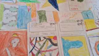 Colourful children's drawings and handwritten notes are spread out on a surface. The vibrant artwork features abstract shapes and simple figures.