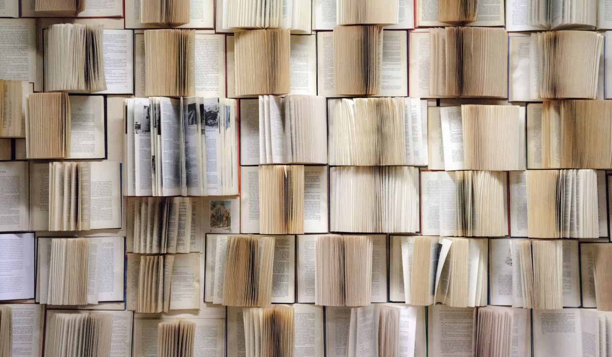 Open books form a dense grid pattern, showcasing a sea of text and pages in varying shades of white and cream, evoking a sense of literary abundance.