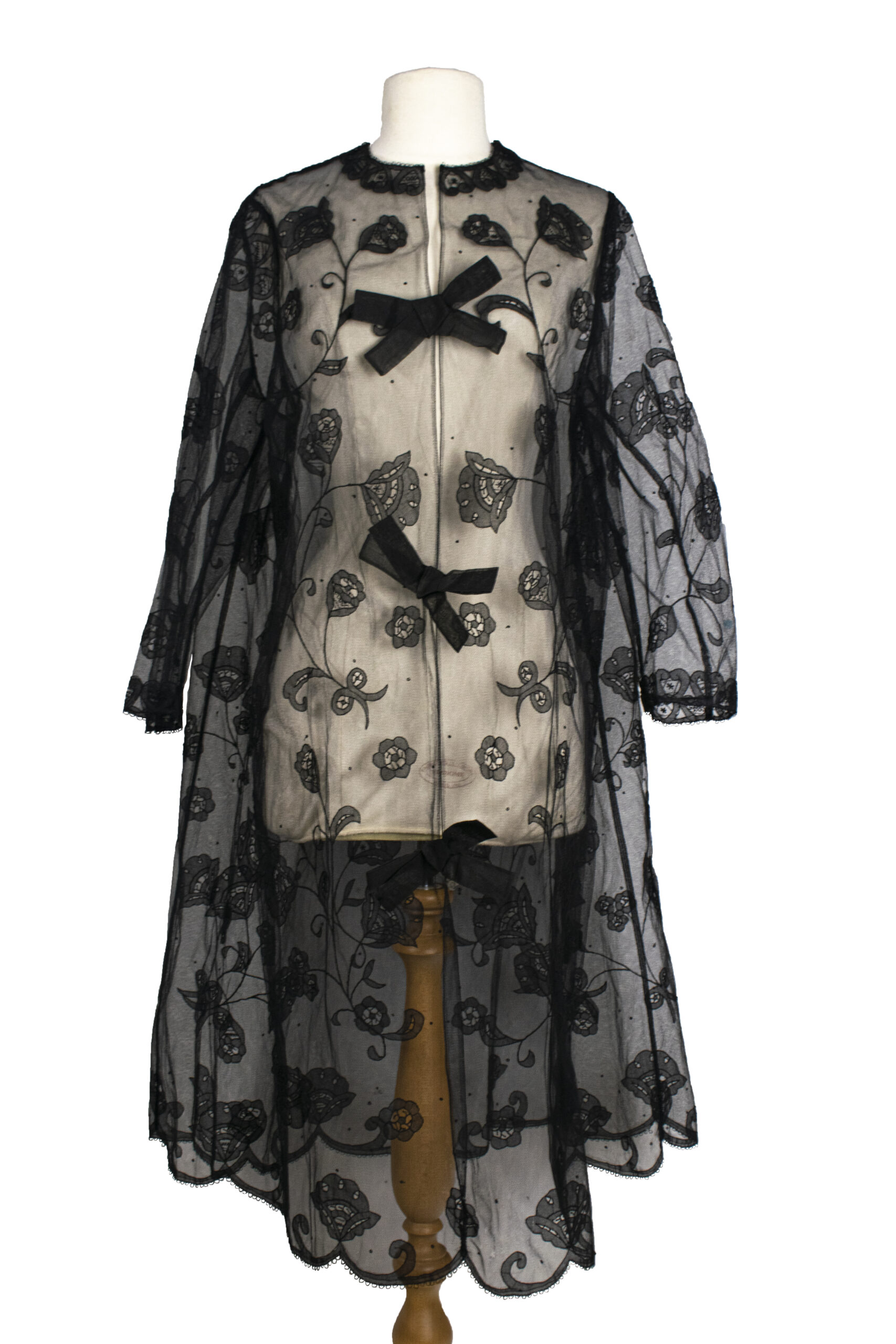 Vintage black lace coat with floral embroidery, sheer overlay, and three large bows on front. Chic and elegant design evokes a classic, timeless style.