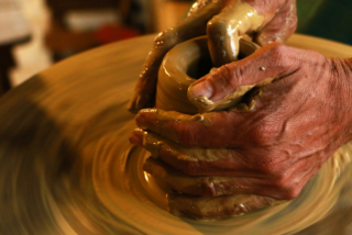 Photo of hands moulding clay on the potter's wheel.