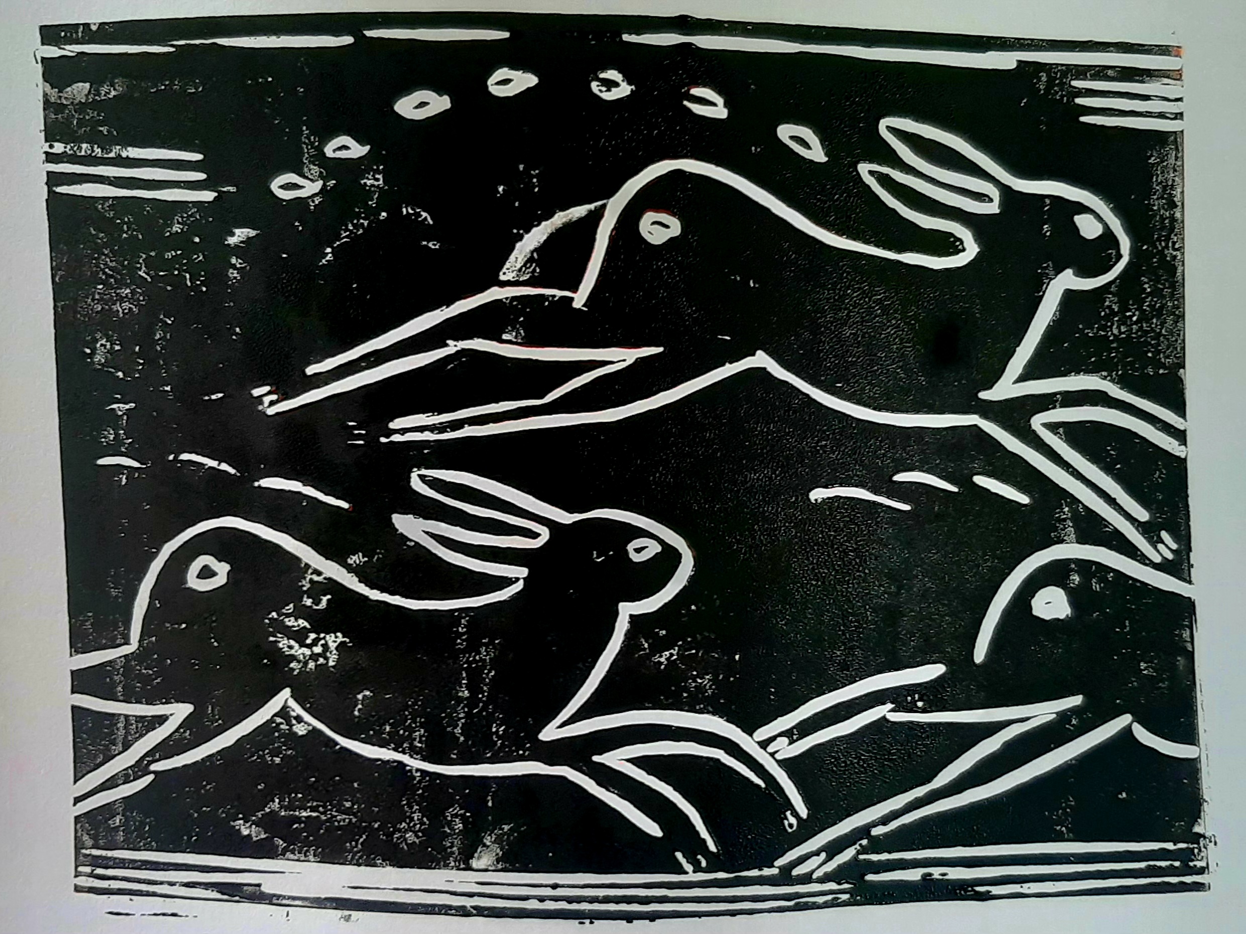 Black and white linocut of three stylized rabbits leaping with dynamic motion lines. The background is textured, conveying a sense of speed and energy.