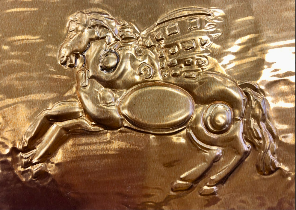 Golden embossed relief of a winged horse with intricate patterns. The metallic surface shines, giving a sense of majesty and craftsmanship.