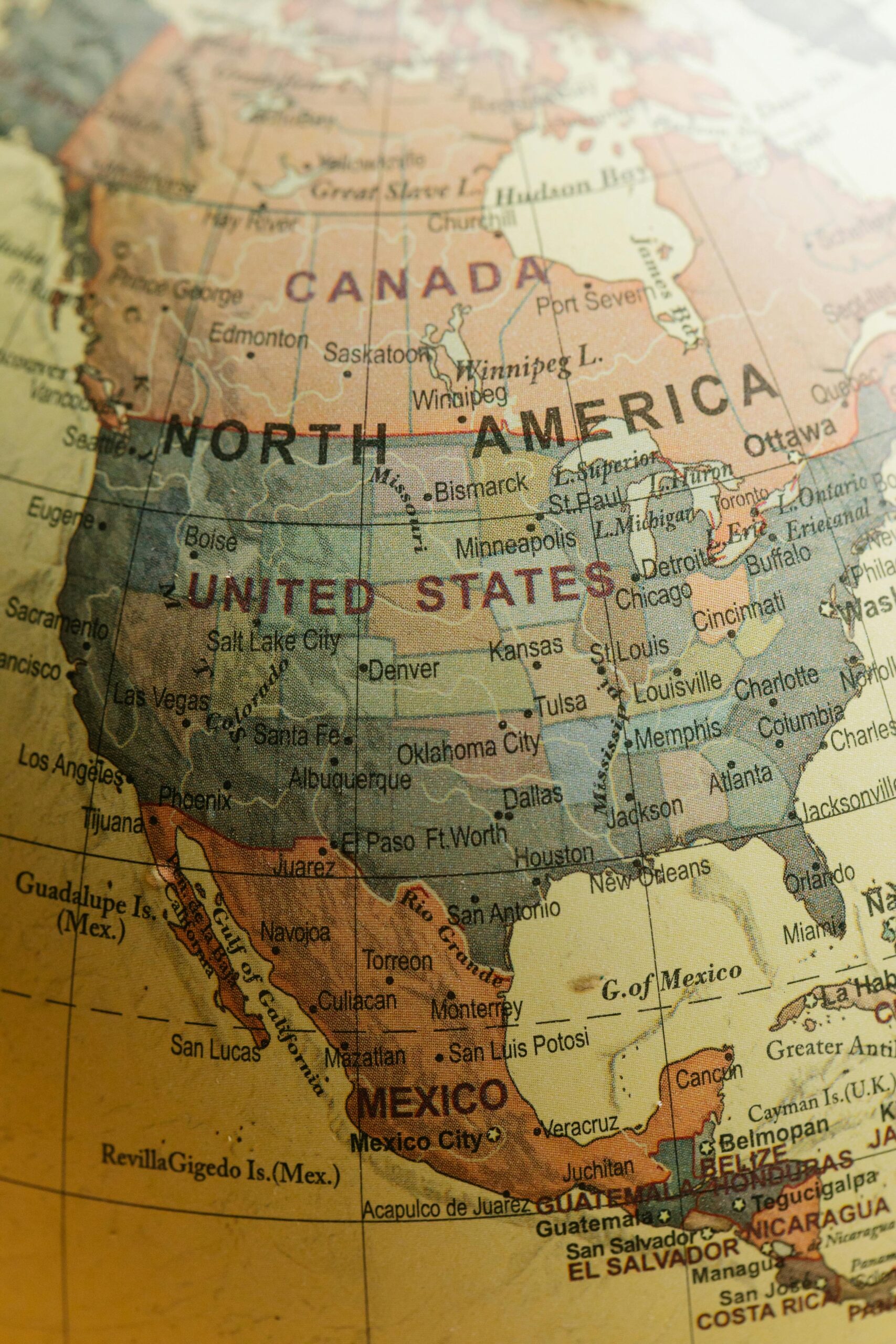 Close-up of a vintage-style globe showing North America, including Canada, the United States, and Mexico. The map has warm tones, evoking a nostalgic feel.