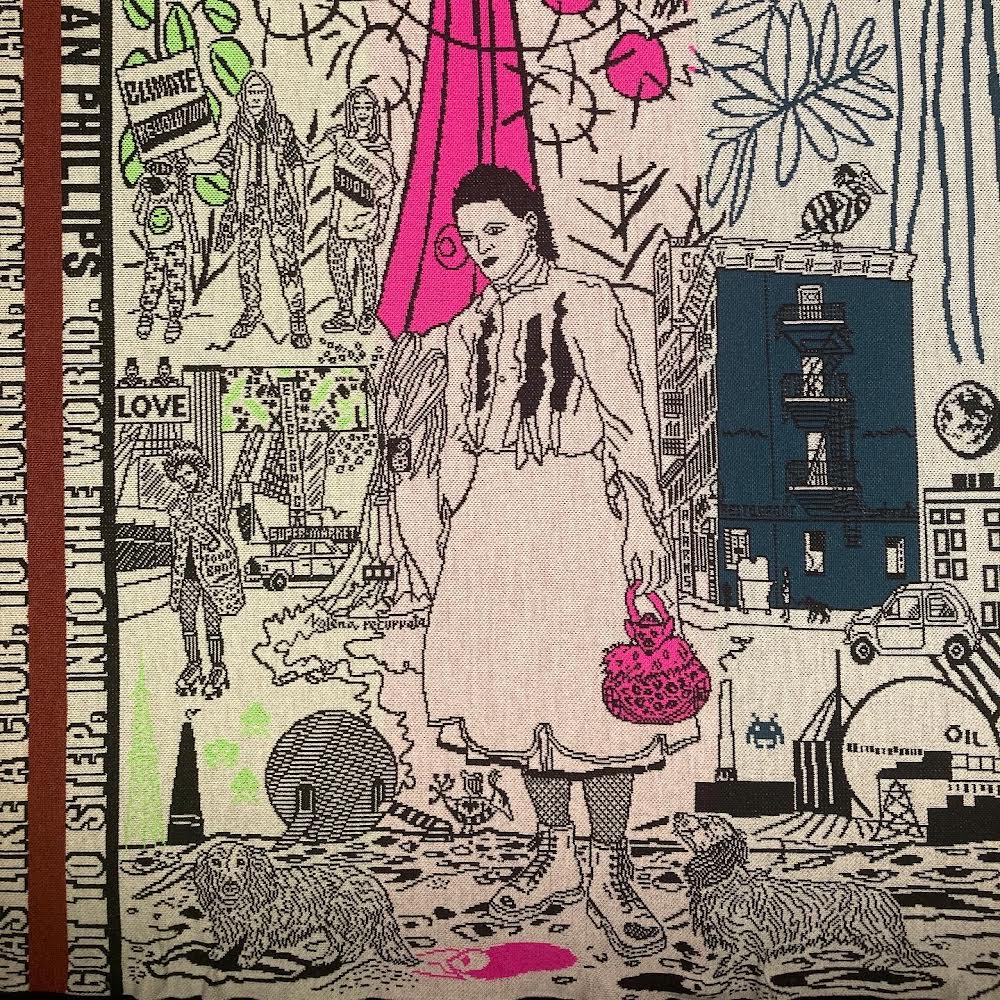 Tapestry depicting a central figure with a pink purse, surrounded by urban scenes. Activists hold 