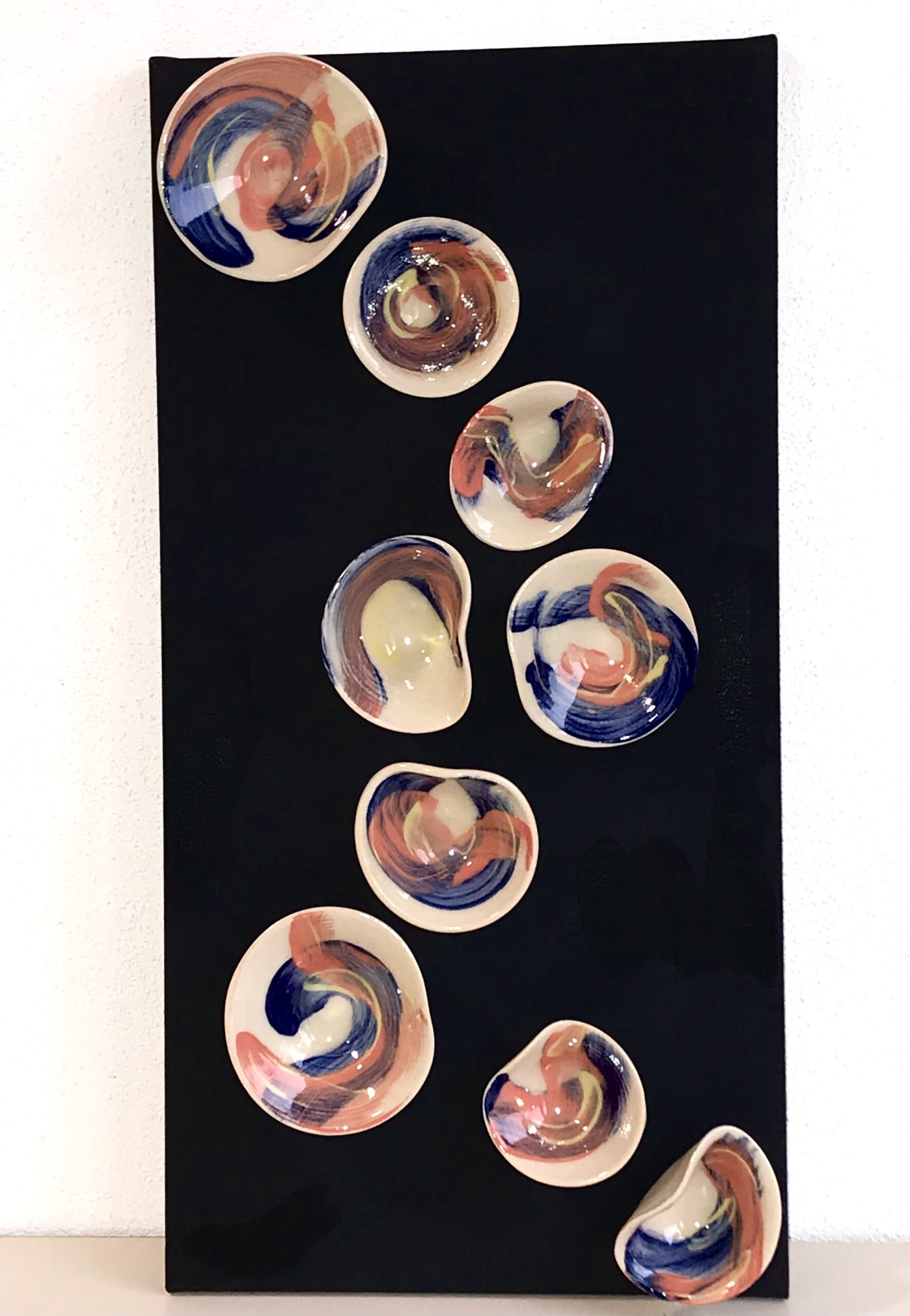 A vertical arrangement of iridescent, multicoloured shells on a black background, showcasing their natural beauty and diversity.