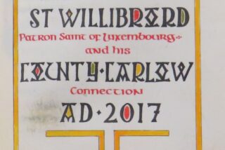 Text in colourful, medieval-style lettering celebrates St. Willibrord, patron saint of Luxembourg, and his connection to County Carlow, AD 2017.