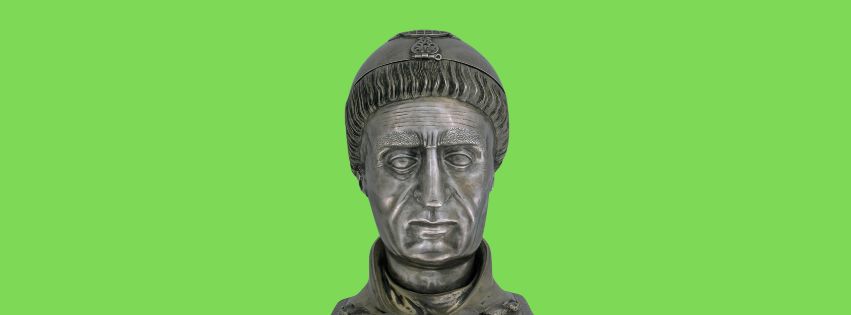 Silver bust of a solemn-faced St. Patrick, detailed with intricate patterns and floral motifs on the collar, vibrant green background.